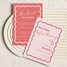 two wedding cards sitting on top of a white plate next to a pink and red card