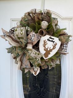 a wreath is hanging on the front door with deer head and antler's horns