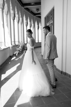 a man and woman standing next to each other in front of a building with columns