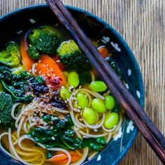 a bowl filled with noodles and vegetables next to chopsticks