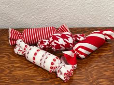 three red and white striped pillows sitting on top of a wooden table next to each other