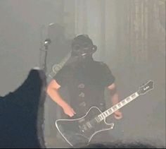 a man wearing a gas mask and holding a guitar