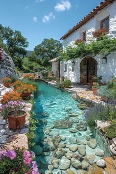 a small stream runs between two buildings with flowers growing on the roof and around it