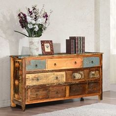 a vase with flowers on top of a wooden dresser next to a book shelf filled with books