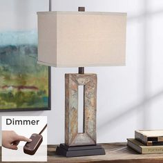 a lamp that is sitting on top of a table next to books and a remote control