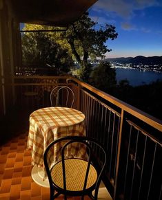 the table and chairs are on the balcony overlooking the lake at night, while the sun is low in the sky