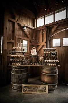 a table topped with lots of wooden barrels filled with cake next to wine glasses and bottles