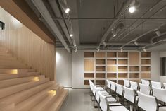 an empty room with white chairs and wooden shelves on the wall, along with stairs