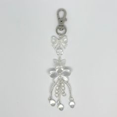 a key chain with bells and pearls hanging from it's side on a white surface