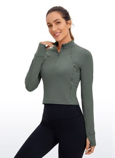 a woman in black pants and a green top posing for the camera with her hand on her hip