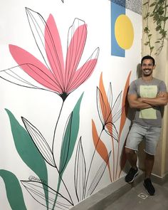 a man standing in front of a wall with flowers painted on it's side