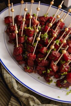 skewered food on a plate with toothpicks and garnishes