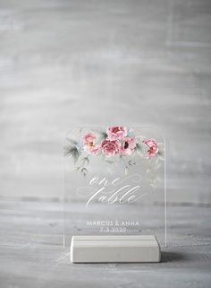 a clear acrylic sign with pink flowers on it