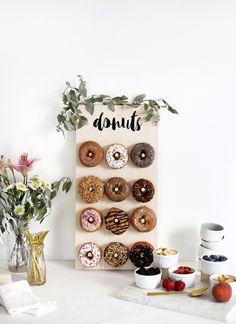 a table topped with donuts next to vases filled with flowers and fruit on top of it