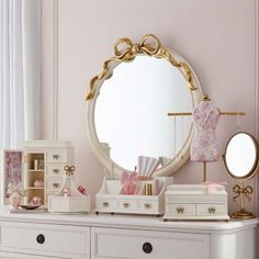 a white dresser topped with lots of drawers and a round mirror