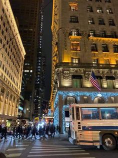 a bus driving down a street next to tall buildings with christmas lights on it's sides