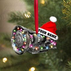 a christmas ornament hanging from a tree with lights and a name on it