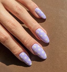 a woman's hand with purple and yellow nail designs on it, sitting on a brown surface