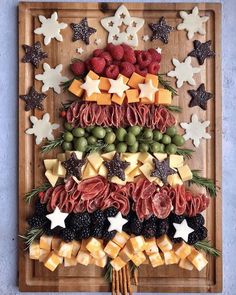 a christmas tree made out of fruits and cheeses on a cutting board with stars