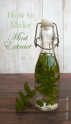 a glass bottle filled with mint leaves on top of a wooden table