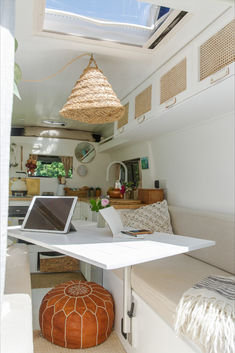 a laptop computer sitting on top of a white table in a living room next to a window