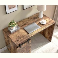 a wooden desk topped with a laptop computer next to a lamp and pictures on the wall