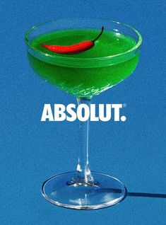 a green cocktail with a red chili on the rim and an absolut logo above it