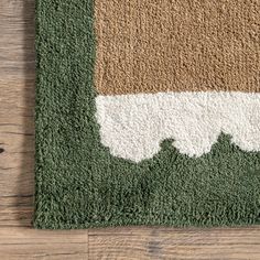 an area rug with green, brown and white colors on the wood floor next to a pair of scissors