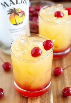 two glasses filled with alcoholic drinks on top of a wooden table