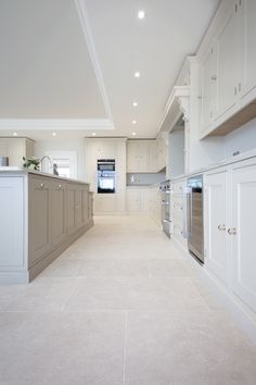 a large kitchen with white cabinets and beige flooring is seen in this image from the hallway