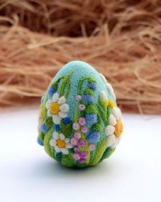 an easter egg decorated with flowers and grass