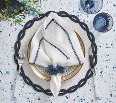 a place setting with white and blue napkins