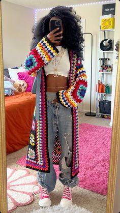 a woman taking a selfie in front of a mirror with her hair styled like an afro