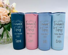 four different colored tumbles sitting next to a vase with flowers in it and the words tamed and tipsy written on them