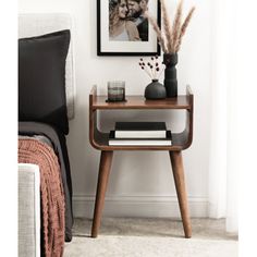 a small wooden table with two vases on it and a framed photo in the background