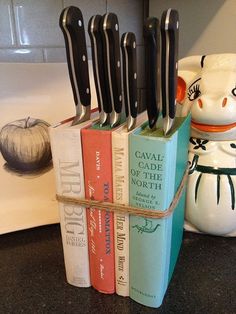 a stack of books sitting on top of a counter next to a knife holder with knives sticking out of it