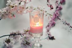 a glass with a candle and some pink flowers