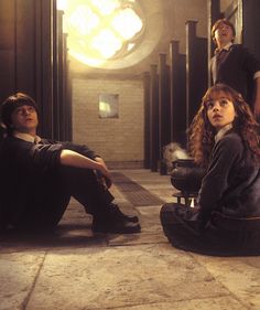 three people sitting on the floor in an empty room with one person looking up at something