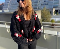 a woman in black sweater and sunglasses standing on top of a roof