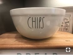 a white bowl sitting on top of a wooden counter next to a sign that says chips