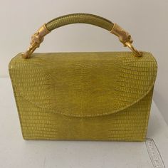 A Stunning Small Structured Handbag From Algo Of Switzerland. Bright Yellow Color With Gold Hardware. A Dyed Embossed Leather Snakeskin Print Exterior. Two Panther, Cat Heads For The Handle. Small Size. Has A Zippered Pocket Inside And A Small Open Pocket. Has Some Loose Threads On Interior Seam And On Bottom Of Bag. Otherwise In Excellent Condition, Comes With Dustbag And Original Receipt And Tag. $1160 Retail Measurements (Approx) 6.5” H X 9” W X 3.5” D 3” Strap Drop Gold Flap Shoulder Bag With Top Carry Handle, Gold Shoulder Flap Bag With Top Carry Handle, Gold Leather Handheld Evening Bag, Chic Formal Bags With Bamboo Handle, Formal Shoulder Bag With Bamboo Handle, Formal Handheld Bags With Bamboo Handle, Yellow Top Handle Box Bag For Evening, Gold Leather Flap Bag With Top Carry Handle, Yellow Box Shoulder Bag For Evening