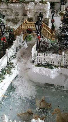 a miniature garden with ducks in the water and snow on the ground next to it