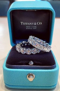 two wedding rings sitting in a blue box