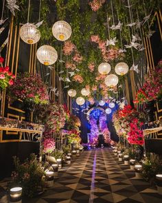 an elaborately decorated garden with hanging lights and flowers on the ceiling is lit by lanterns