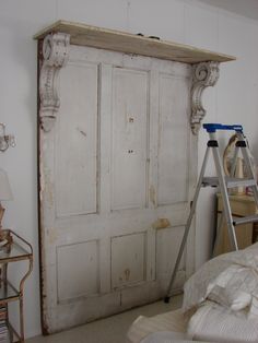 an old door is being painted white in a bedroom with a ladder leaning against it