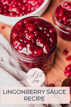 a jar filled with cranberry sauce on top of a wooden table next to two bowls