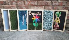 three wooden frames with different items in them and the words breathe painted on them, sitting against a brick wall