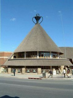 a building with a thatched roof and people walking around