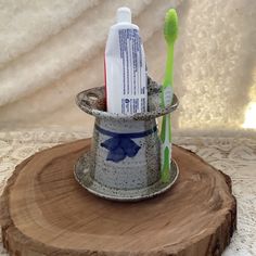 two toothbrushes in a cup on top of a tree stump