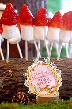 strawberries and marshmallows are on sticks in front of a forest theme